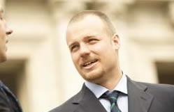 Businessman in a suit having a conversation outside a government or corporate building.
