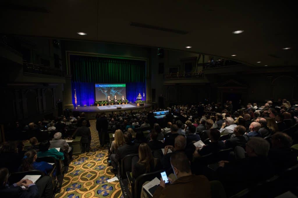 Wide view of a packed auditorium at Regent University during the inaugural Cybersecurity Summit with audience members attentively listening.