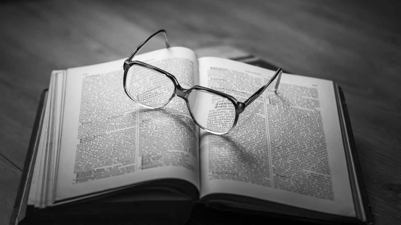 Glasses on an open book: Explore the Master of Theological Studies MTS degree program offered by Regent online / Virginia.