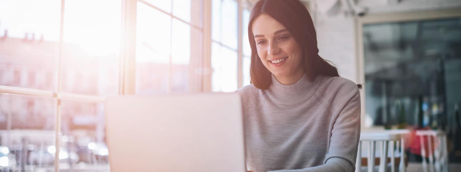 A lady looking at her laptop: Explore the Bachelor of Science in Professional Studies - Communication Studies program offered by Regent University.