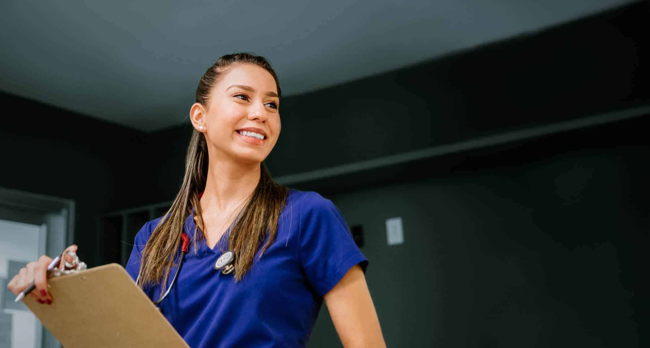 A nurse holding a clipboard: Explore Regent's RN to B.S. in Nursing program online.