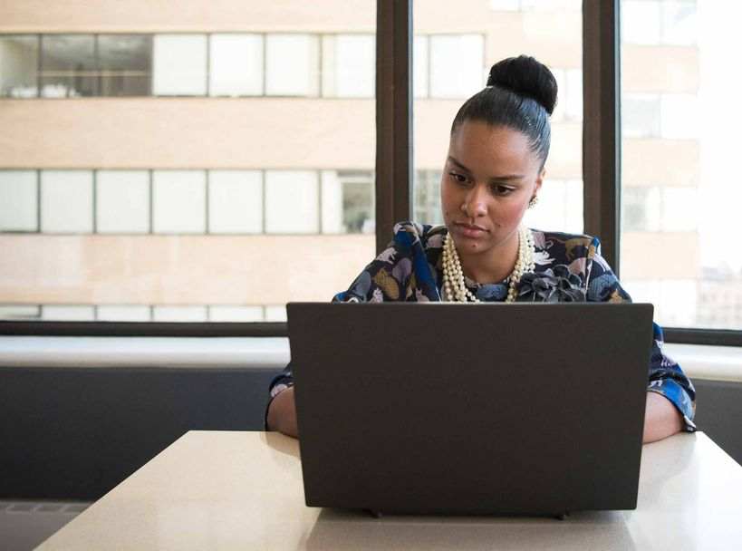 A woman pursuing her business analytics degree works on her laptop.