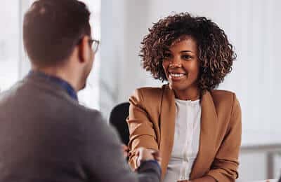Two professionals in conversation: Access job posting at Regent University's career services.