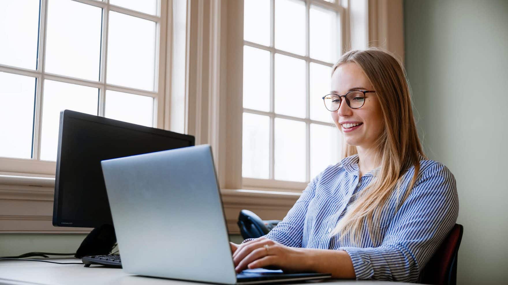 A student working on her laptop: Learn about webinars and workshops hosted by Regent University.