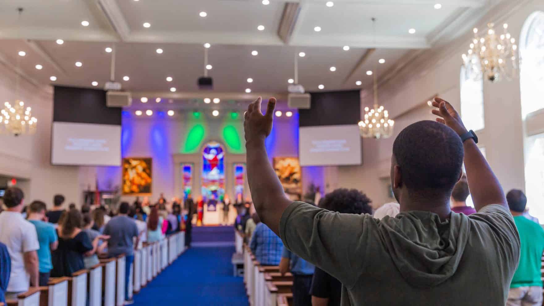 A person with arms outstretched at Regent University’s chapel in Virginia Beach.