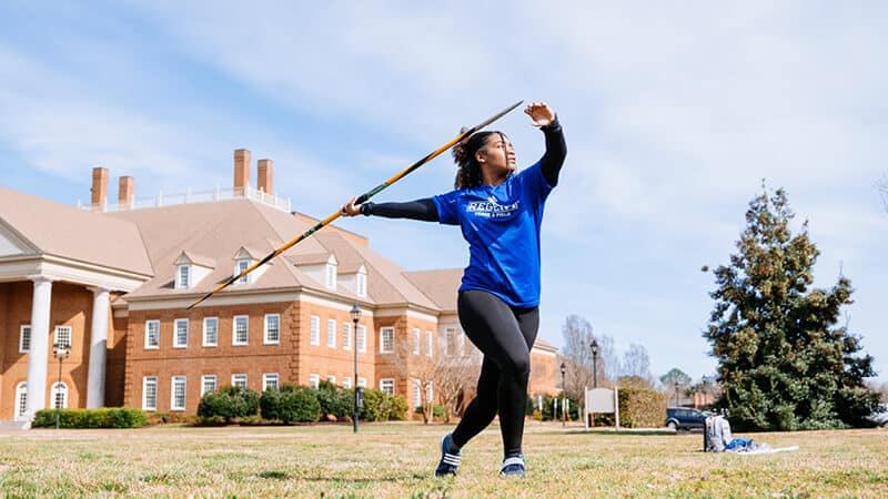 Marelly Balentina practicing javelin on Regent University lawn in athletic gear