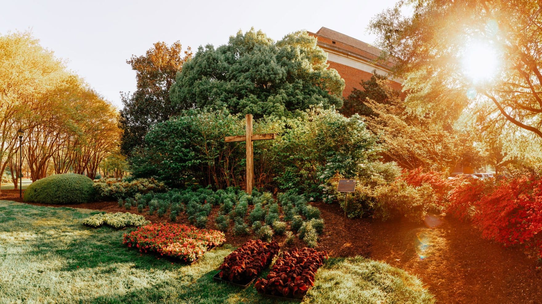 A wooden cross surrounded by colorful landscaped gardens on Regent University's campus