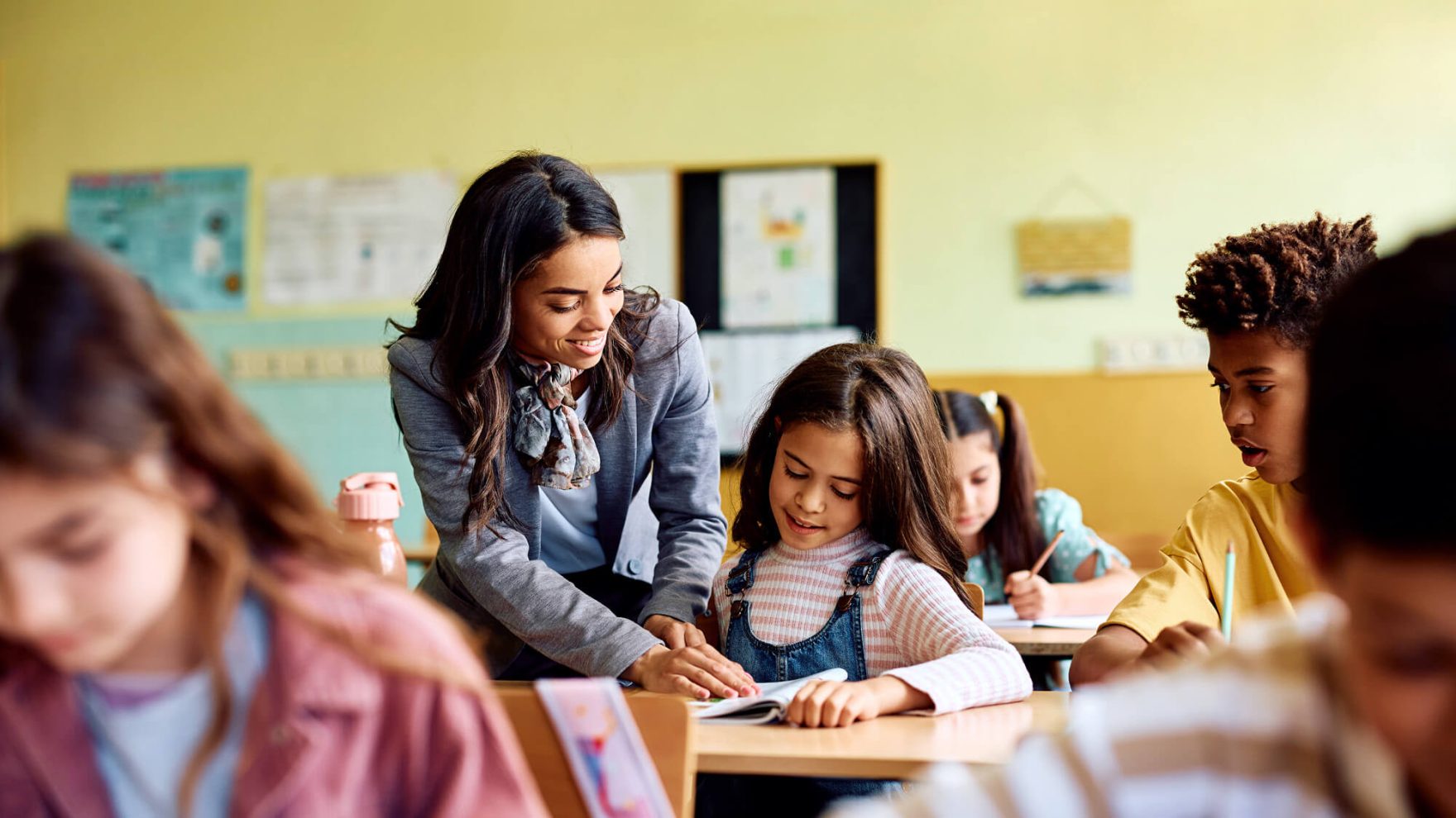 Teacher helping a student in a classroom.