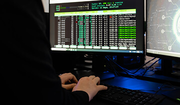 Technician's hands managing network cables and patch panels in a server room illuminated by blue light