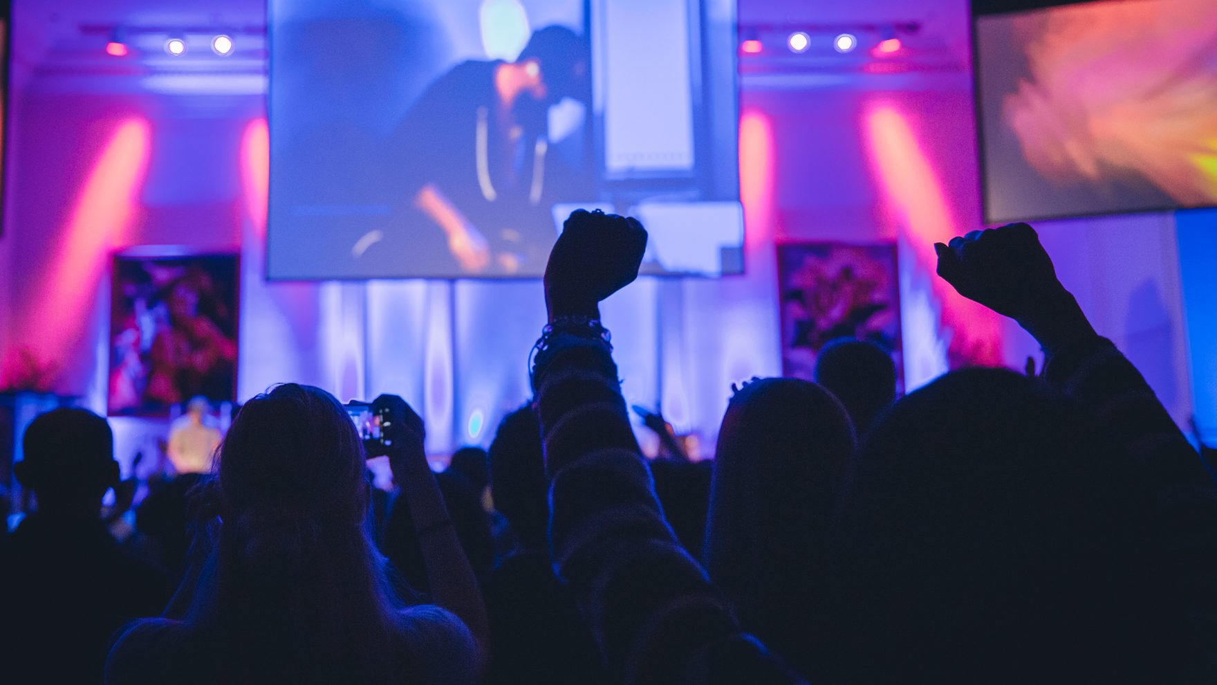 Students raising their hands in worship during a live chapel service at Regent University