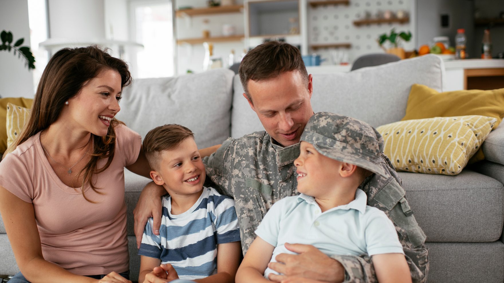 An active U.S. military soldier sitting in the living room with his wife and two sons.