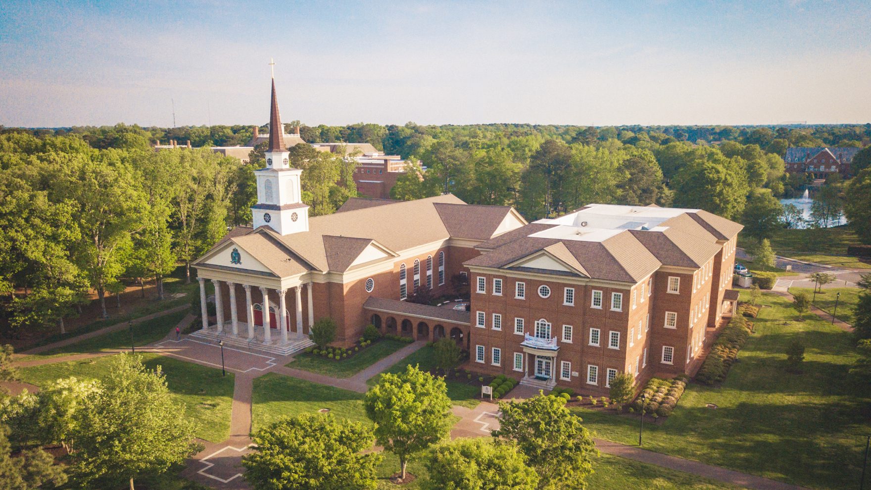 Photo of Regent University's Shaw Chapel Building and Divinity Building, standing side by side surrounded by trees on the university's campus, located in Virginia Beach, Virginia.